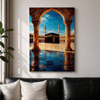 Framed wall art showing the Kaaba at Masjid Al Haram in Mecca viewed through a grand marble archway with columns and reflective courtyard tiles under a bright blue sky.