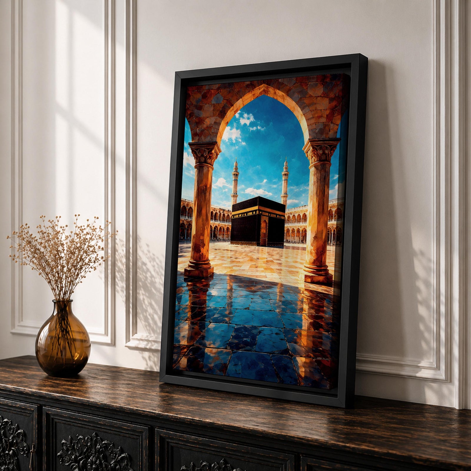 Framed wall art showing the Kaaba at Masjid Al Haram in Mecca viewed through a grand marble archway with columns and reflective courtyard tiles under a bright blue sky.