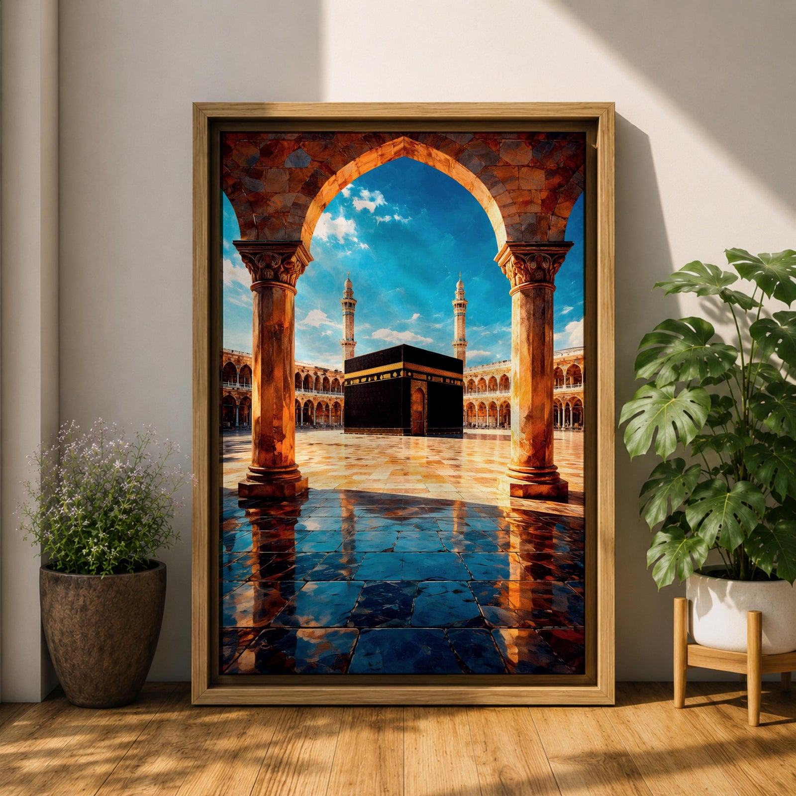 Framed wall art showing the Kaaba at Masjid Al Haram in Mecca viewed through a grand marble archway with columns and reflective courtyard tiles under a bright blue sky.