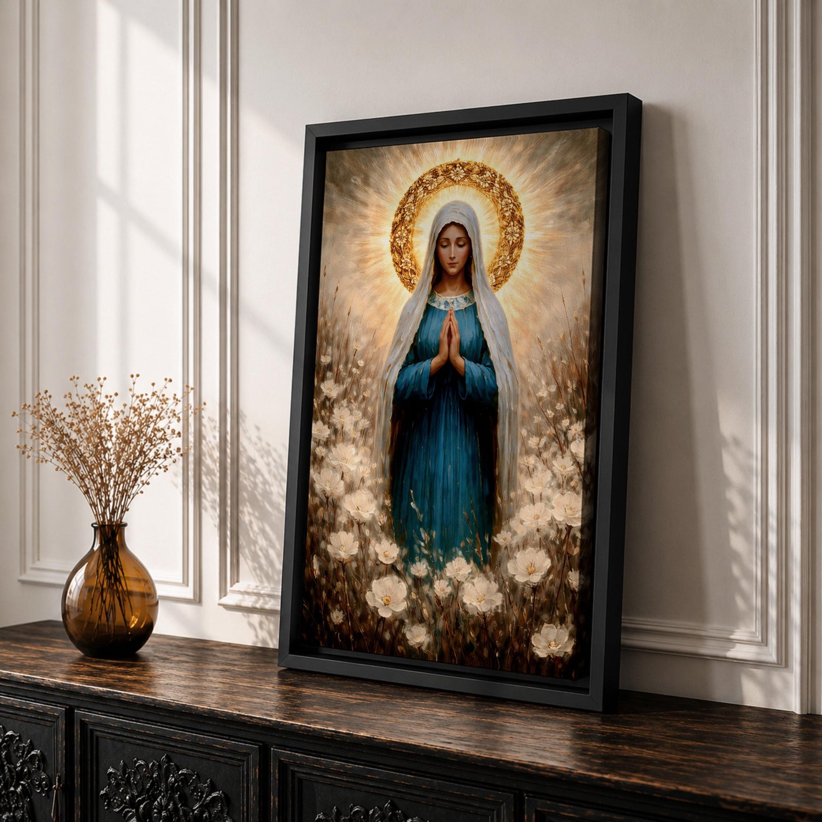 Painting of the Virgin Mary standing in prayer with hands clasped and head bowed, wearing a flowing blue robe and white veil, surrounded by a radiant golden halo and soft glowing light while standing within a field of delicate white wildflowers in a devotional Marian composition.