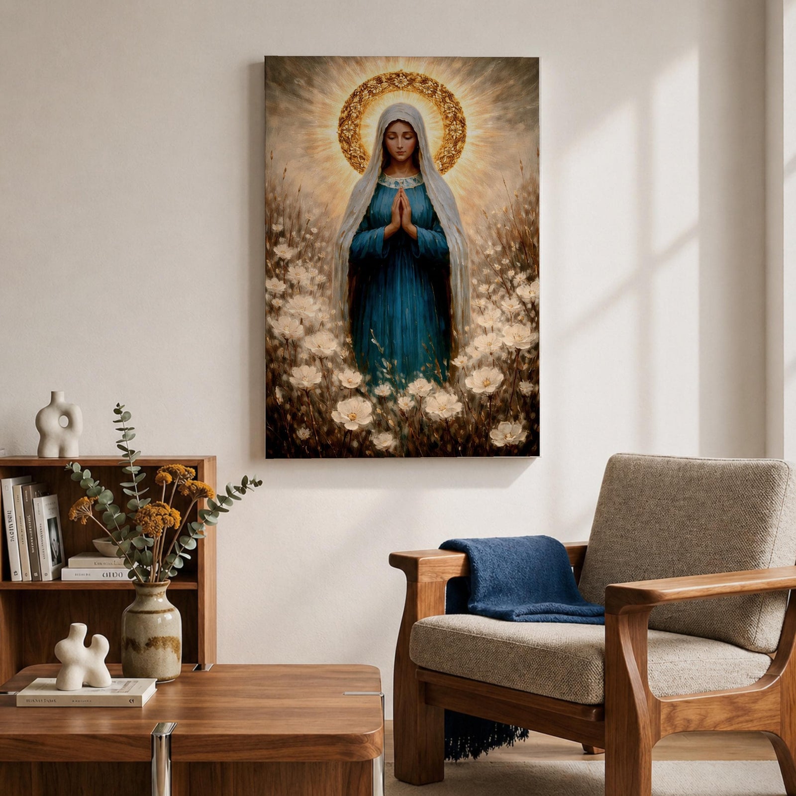 Painting of the Virgin Mary standing in prayer with hands clasped and head bowed, wearing a flowing blue robe and white veil, surrounded by a radiant golden halo and soft glowing light while standing within a field of delicate white wildflowers in a devotional Marian composition.