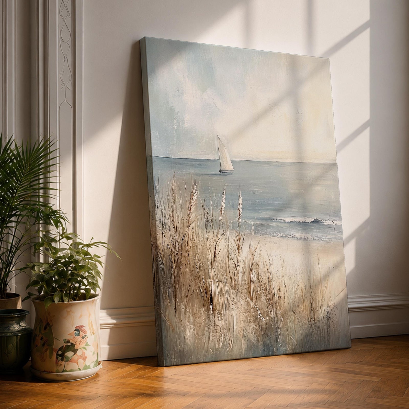 A vintage-style framed canvas painting depicting a sailboat on calm coastal waters with gentle waves and tall beach grasses in the foreground. The artwork captures a serene beach landscape with soft textures and muted tones, evoking a rustic farmhouse coastal aesthetic.