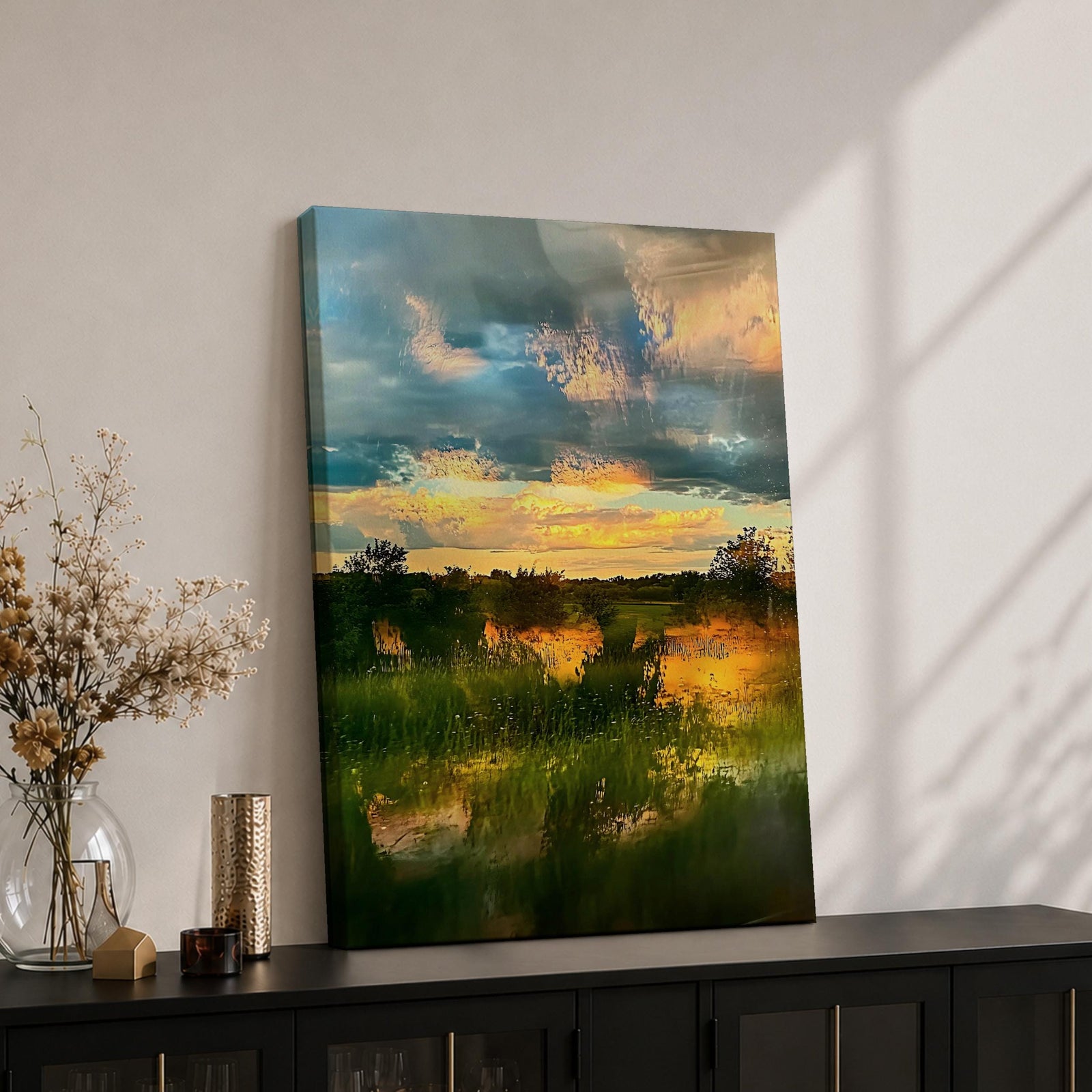 A framed vintage-style artwork depicting a sunset landscape with a serene country scene featuring grassy fields, trees, and a dramatic sky with clouds reflecting warm light, rendered in a painterly vintage aesthetic emphasizing natural beauty and tranquility.