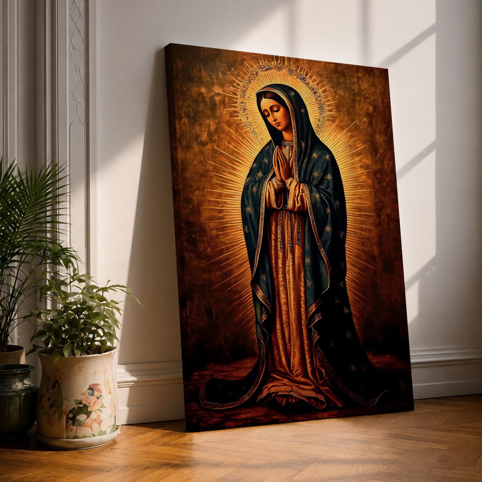 Painting of Our Lady of Guadalupe standing with hands clasped in prayer, wearing a long rose gown and dark star covered mantle, surrounded by radiant golden rays forming a halo behind her figure. The composition presents the Virgin in a traditional devotional icon style with serene expression and symmetrical vertical framing.