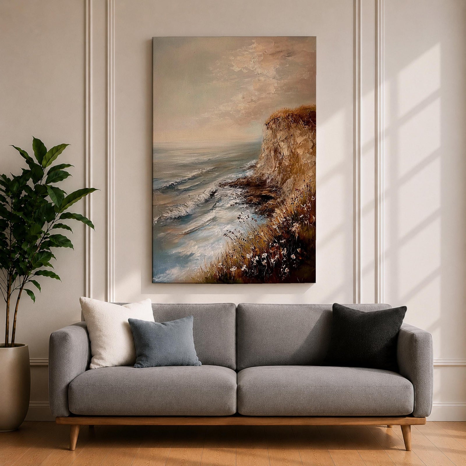 A vintage style framed canvas painting depicting a cliffside ocean seascape with waves crashing against rocky shores and wildflowers in the foreground. The textured brushwork captures the coastal landscape atmosphere with muted tones and a soft sky blending into the horizon.