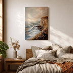 A vintage style framed canvas painting depicting a cliffside ocean seascape with waves crashing against rocky shores and wildflowers in the foreground. The textured brushwork captures the coastal landscape atmosphere with muted tones and a soft sky blending into the horizon.