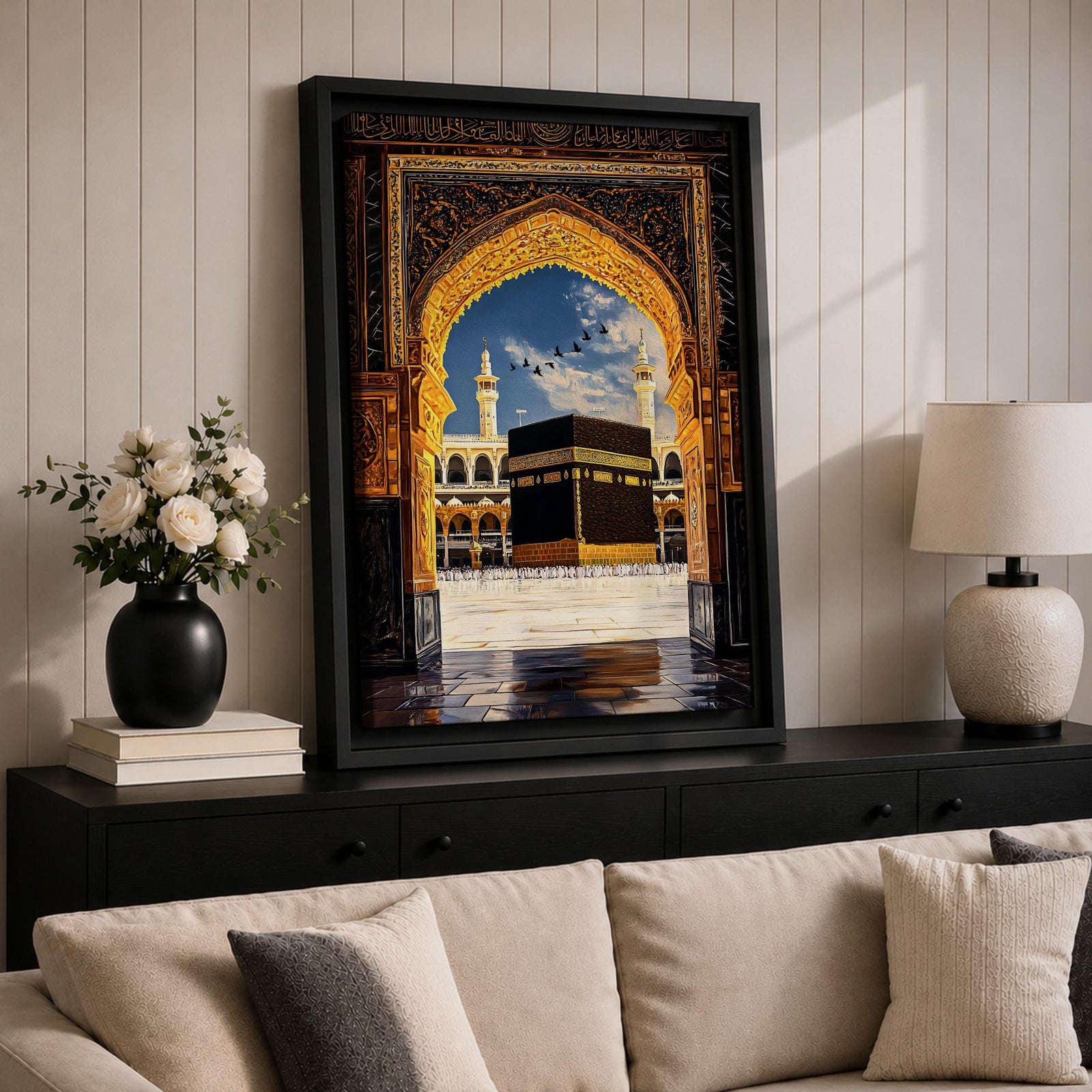 Artwork depicting the Kaaba in Masjid Al Haram in Mecca viewed through an ornate golden mosque arch, with two tall minarets rising behind the sacred courtyard and birds flying across a bright blue sky.