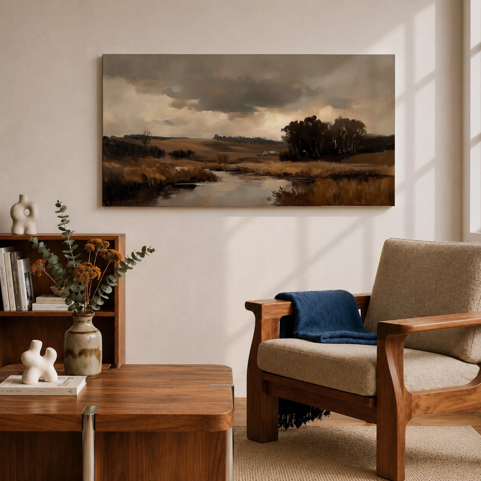A panoramic countryside river landscape painting featuring a calm winding stream flowing through open rural fields with tall golden grasses and a distant farmhouse near a cluster of dark trees beneath a dramatic cloudy sky. The scene uses earthy browns and muted greens with soft painterly brushstrokes capturing a quiet pastoral prairie setting.