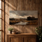 A panoramic countryside river landscape painting featuring a calm winding stream flowing through open rural fields with tall golden grasses and a distant farmhouse near a cluster of dark trees beneath a dramatic cloudy sky. The scene uses earthy browns and muted greens with soft painterly brushstrokes capturing a quiet pastoral prairie setting.
