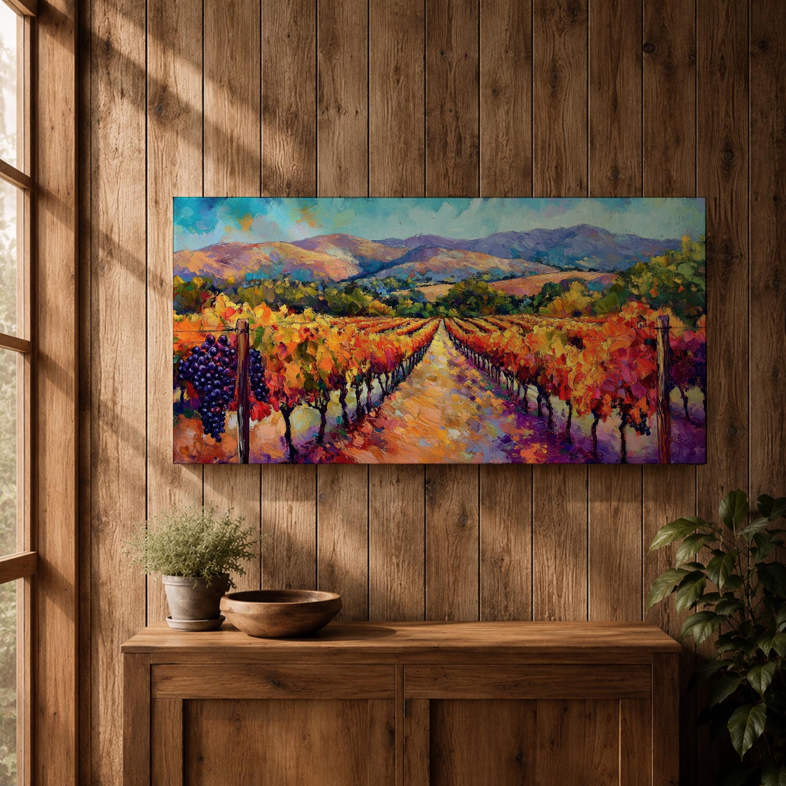 A panoramic vineyard landscape painting showing long rows of grapevines covered in red and golden autumn leaves stretching toward distant mountains beneath a bright sky. Purple grape clusters hang beside the vines while a central path leads through the field, capturing a colorful wine country valley with bold impressionist brushstrokes.