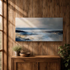 Panoramic abstract coastal seascape painting featuring a calm ocean shoreline with soft blue, gray, and sandy tones reflecting across the water beneath a cloudy horizon.