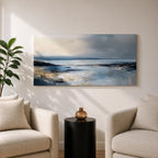 Panoramic abstract coastal seascape painting featuring a calm ocean shoreline with soft blue, gray, and sandy tones reflecting across the water beneath a cloudy horizon.