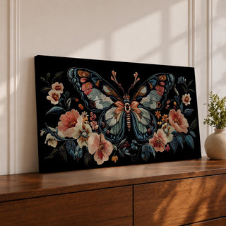Panoramic artwork depicting a large symmetrical butterfly with intricate patterned wings in blue, cream, and rust tones surrounded by blooming flowers and leafy botanical elements. The composition resembles detailed embroidered textile artwork set against a deep black background with balanced floral arrangements framing the butterfly.