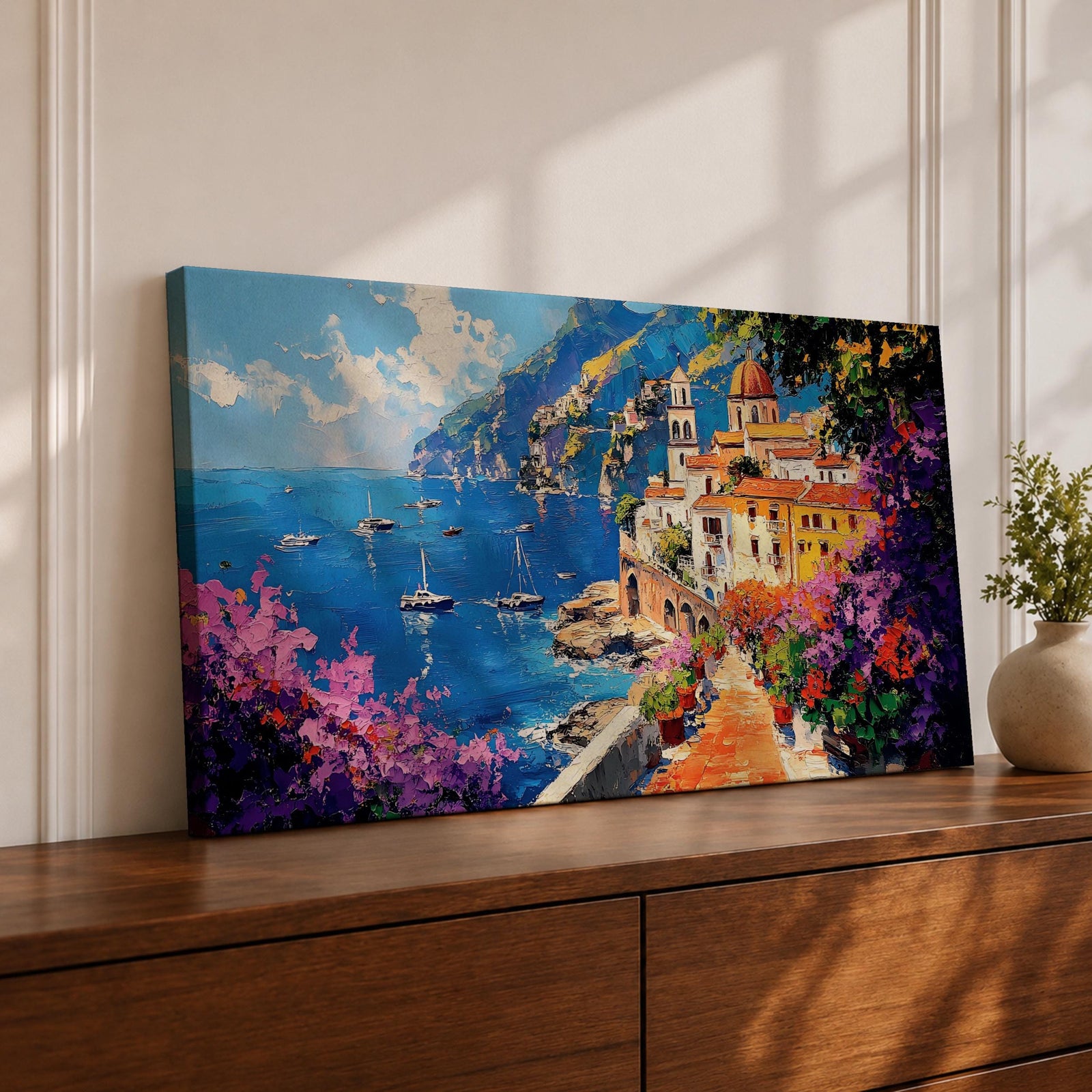 Panoramic painting of the Amalfi Coast featuring a colorful seaside village perched above deep blue Mediterranean water. Boats float across the bay while a stone path lined with blooming bougainvillea leads toward warm sunlit buildings and a domed church, with dramatic coastal cliffs and mountains rising in the distance.