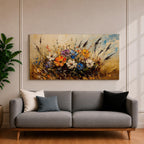 Panoramic painting depicting a vibrant cluster of wildflowers growing through tall meadow grasses. Bright blossoms in orange, blue, purple, and white rise from textured golden stems while loose expressive brushstrokes create movement across the floral arrangement and surrounding field.