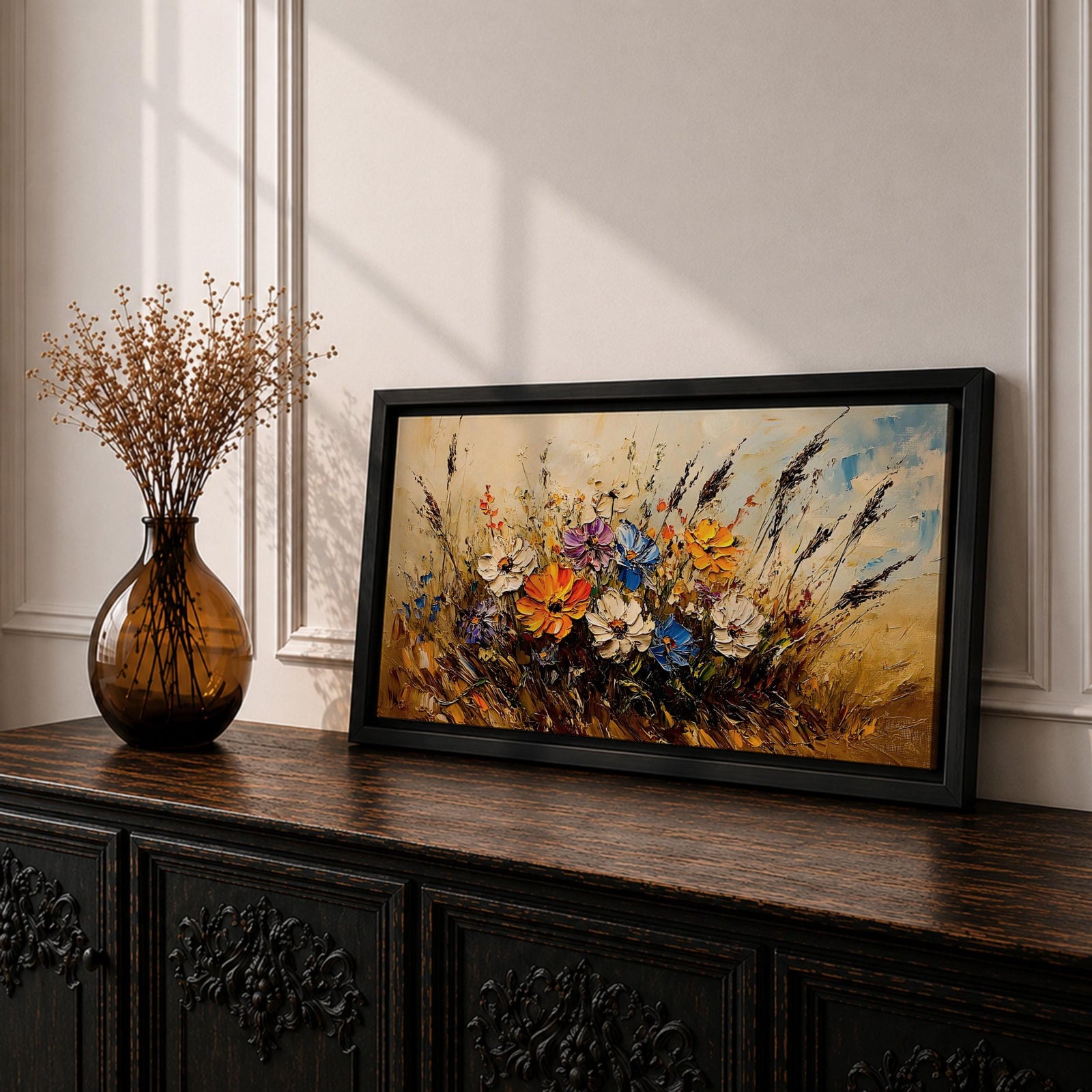 Panoramic painting depicting a vibrant cluster of wildflowers growing through tall meadow grasses. Bright blossoms in orange, blue, purple, and white rise from textured golden stems while loose expressive brushstrokes create movement across the floral arrangement and surrounding field.