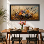 Panoramic painting depicting a vibrant cluster of wildflowers growing through tall meadow grasses. Bright blossoms in orange, blue, purple, and white rise from textured golden stems while loose expressive brushstrokes create movement across the floral arrangement and surrounding field.
