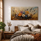 Panoramic painting depicting a vibrant cluster of wildflowers growing through tall meadow grasses. Bright blossoms in orange, blue, purple, and white rise from textured golden stems while loose expressive brushstrokes create movement across the floral arrangement and surrounding field.
