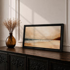 Panoramic coastal landscape painting showing a quiet sandy beach with gentle ocean waves rolling onto the shore beneath a soft sky. Subtle tones of beige, blue, and warm gray create a calm atmosphere while distant hills stretch along the horizon and light reflects across the water.