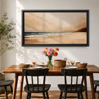 Panoramic coastal landscape painting showing a quiet sandy beach with gentle ocean waves rolling onto the shore beneath a soft sky. Subtle tones of beige, blue, and warm gray create a calm atmosphere while distant hills stretch along the horizon and light reflects across the water.