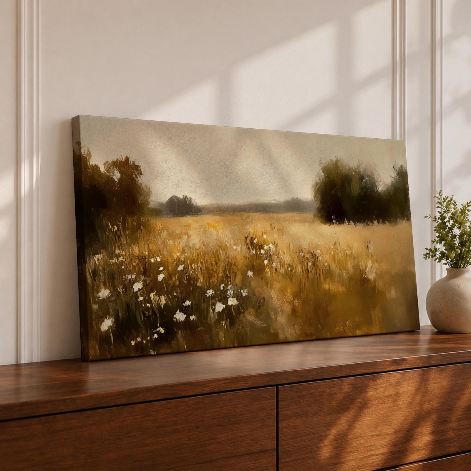 A panoramic painting of a golden meadow filled with tall grasses and scattered white wildflowers stretching across an open countryside field toward a distant horizon, bordered by darker tree clusters and rendered with soft impressionist brushstrokes in warm earthy tones that create depth and a quiet rural atmosphere.