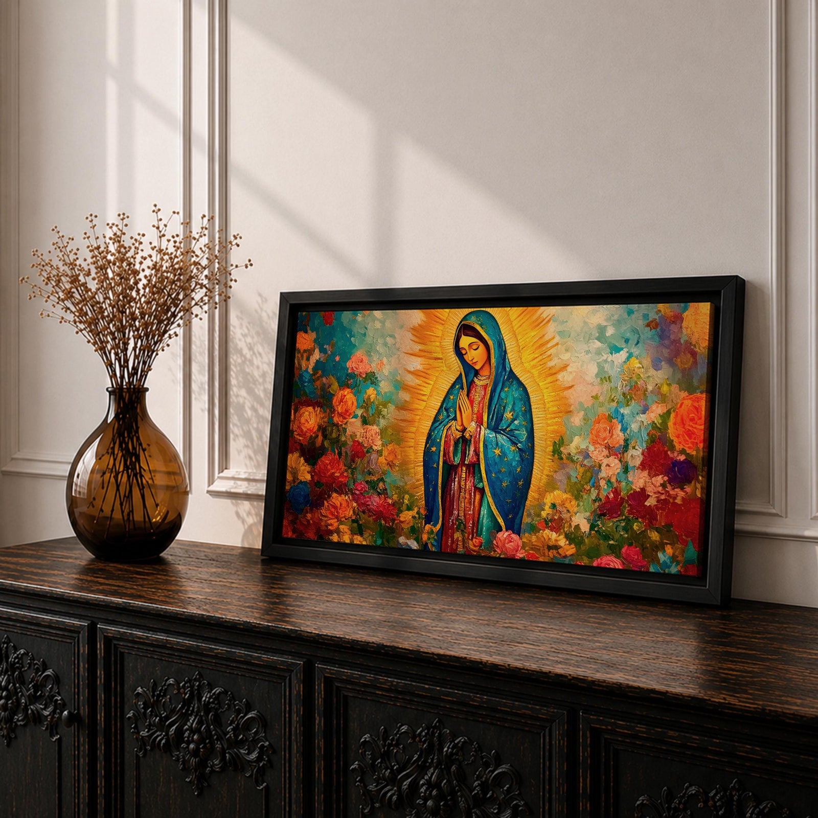 A panoramic painting of the Virgin Mary depicted as Our Lady of Guadalupe standing in prayer with hands together, wearing a blue star covered mantle and red dress, surrounded by radiant golden light and vibrant blooming flowers in rich reds, pinks, and oranges painted with expressive textured brushstrokes.