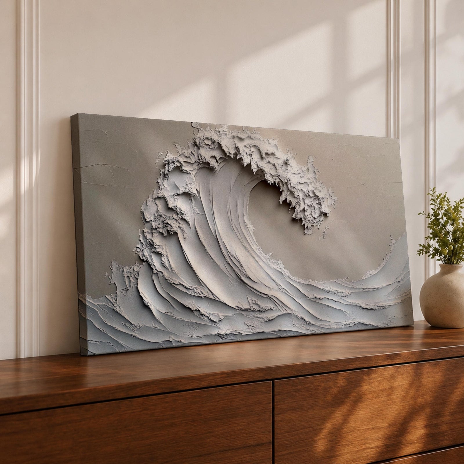 Panoramic textured relief artwork depicting a powerful ocean wave curling upward in sculpted layered forms. The cresting breaker is rendered with thick plaster like ridges and flowing contours in soft neutral tones, creating a minimalist seascape with depth and movement across the wide horizontal composition.