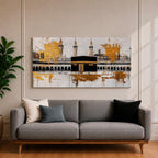 Panoramic painting of the Kaaba in Mecca centered within Masjid al Haram featuring the black cube sanctuary draped in the kiswah with gold calligraphy bands. Tall mosque minarets and long arched colonnades frame the courtyard while bold gold abstract paint textures and layered architectural lines extend across the wide horizontal composition.