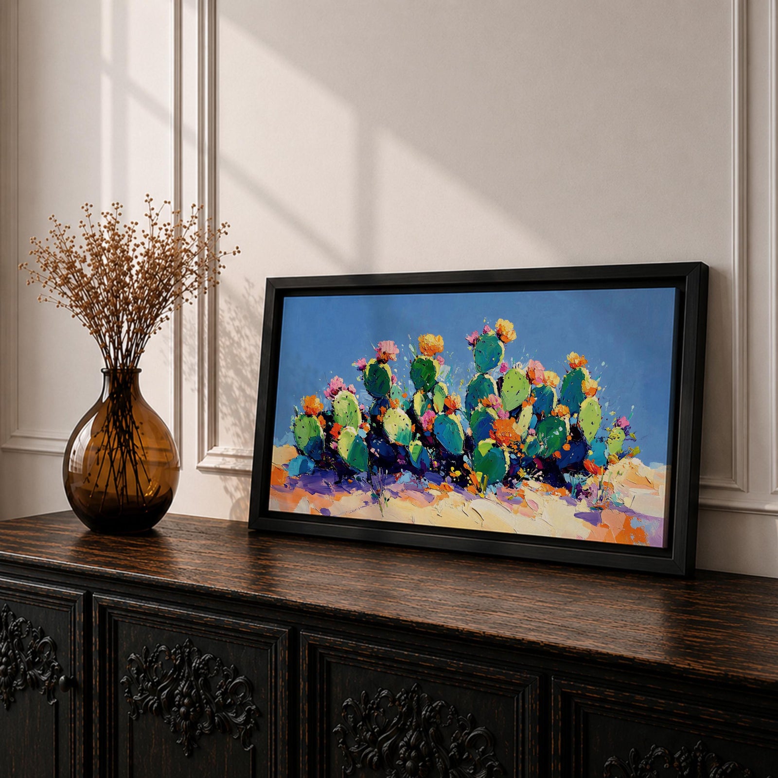 Panoramic painting of desert prickly pear cactus plants with bright pink and yellow blooming flowers growing across a colorful arid landscape. Thick palette knife brushstrokes create textured cactus pads vibrant blossoms and layered desert hills beneath a glowing sky forming a wide southwestern desert scene.
