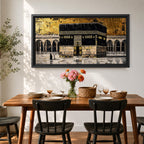 Panoramic gold and black painting of the Kaaba at Masjid al Haram in Mecca, showing the cubed sanctuary draped in the black kiswah with gold calligraphy bands. Surrounding mosque arches and marble courtyard stretch across the horizontal composition while small pilgrim figures circle the Kaaba creating scale and depth.