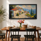 Panoramic painting of a Mediterranean hillside village with warm stone houses and terracotta roofs overlooking the rolling Tuscany hills. Thick palette knife brushstrokes create textured buildings cypress trees and layered green landscapes beneath a glowing sky forming a wide Italian countryside scene.