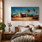 Panoramic painting of a Moroccan kasbah built from warm earthen walls set in a desert landscape with tall palm trees and distant snow capped mountains beneath a bright blue sky. Thick palette knife textures shape the fortress architecture sandy ground and foliage creating a wide horizontal North African landscape scene with bold contrast.