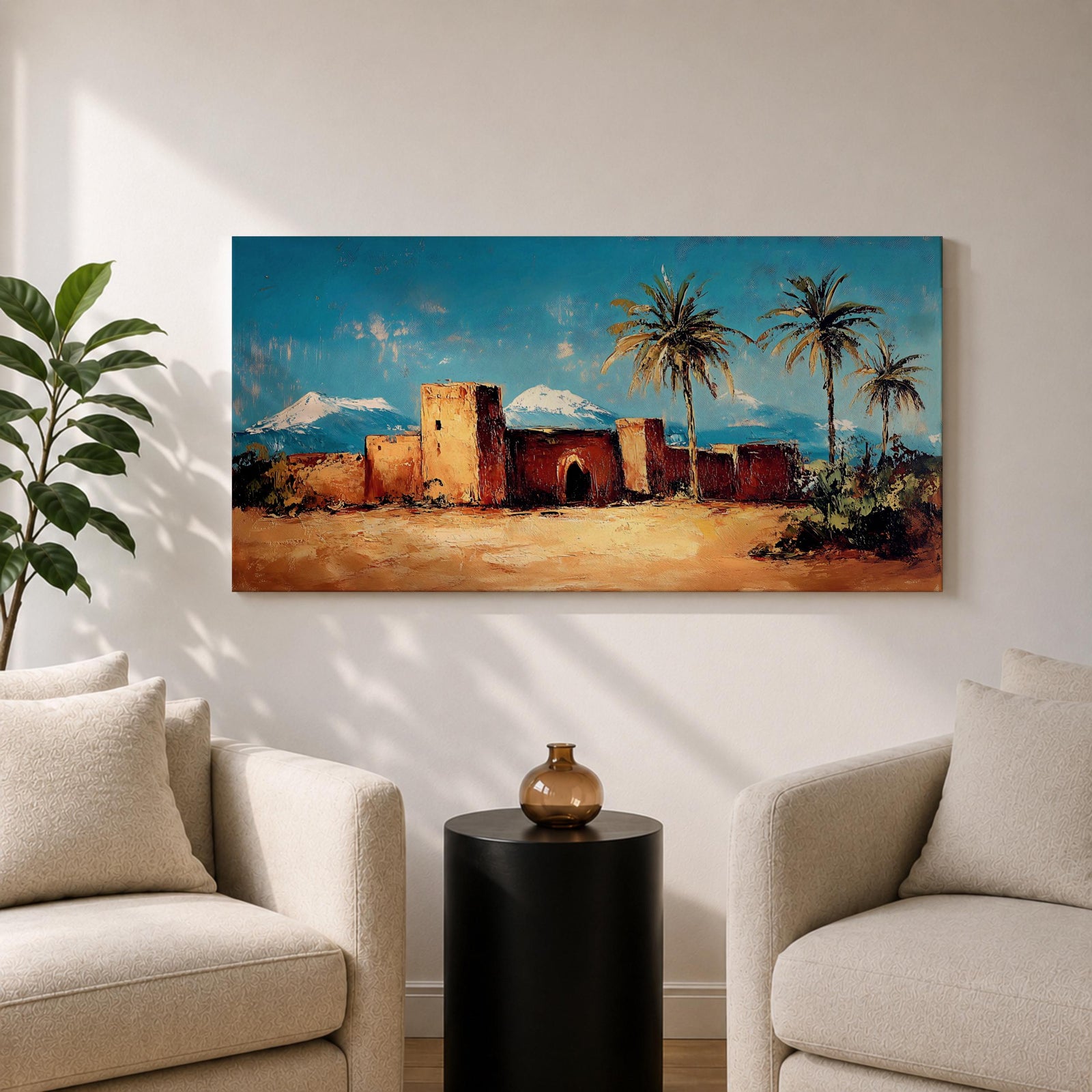 Panoramic painting of a Moroccan kasbah built from warm earthen walls set in a desert landscape with tall palm trees and distant snow capped mountains beneath a bright blue sky. Thick palette knife textures shape the fortress architecture sandy ground and foliage creating a wide horizontal North African landscape scene with bold contrast.