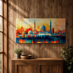 Panoramic abstract painting of Al Masjid an Nabawi in Medina featuring the mosque domes and tall minarets with the iconic green dome at the center. The architecture is rendered with geometric block brushstrokes in vibrant blues, reds, yellows and oranges creating a modern cityscape style composition.