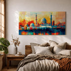 Panoramic abstract painting of Al Masjid an Nabawi in Medina featuring the mosque domes and tall minarets with the iconic green dome at the center. The architecture is rendered with geometric block brushstrokes in vibrant blues, reds, yellows and oranges creating a modern cityscape style composition.