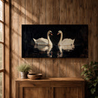 Panoramic painting of two white swans facing each other on dark reflective water with graceful curved necks forming a symmetrical composition. The birds glow against a deep black background with shimmering reflections and textured brushstrokes highlighting feathers and light across the calm water surface.