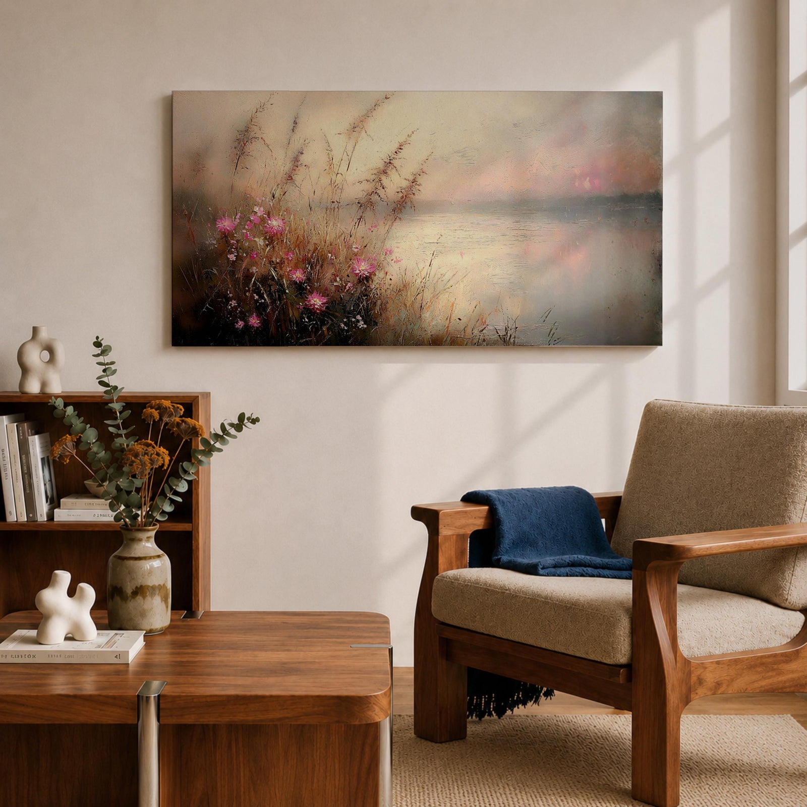 Panoramic landscape painting of soft pink wildflowers and tall grasses growing along a calm lakeshore. The scene features delicate meadow blooms in the foreground with textured brushstrokes and warm earthy tones, fading into a misty reflective lake and distant horizon under a gentle sky.