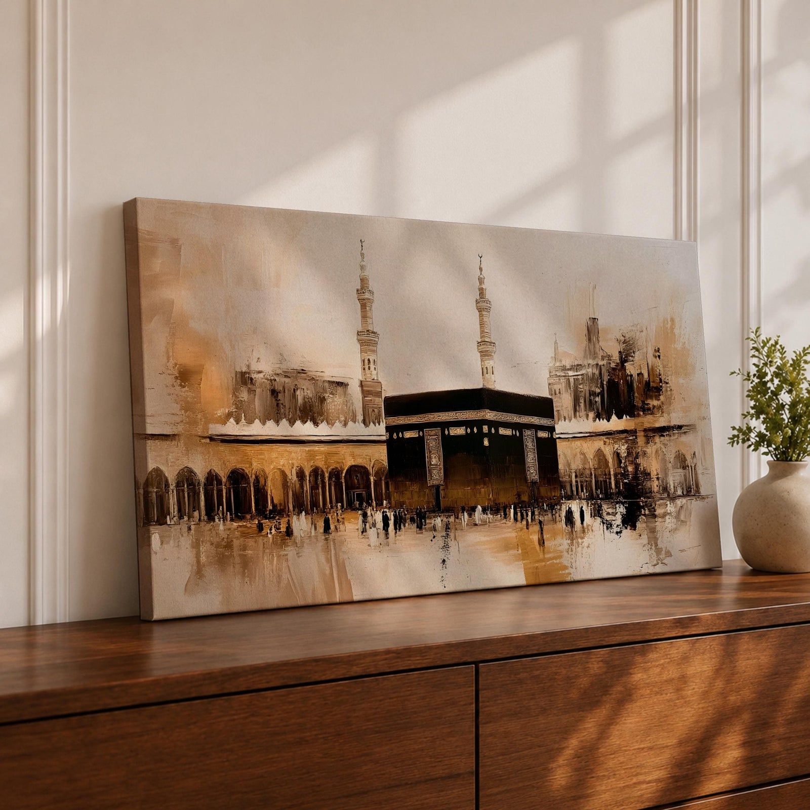Panoramic painting of the Kaaba at Masjid al Haram in Mecca surrounded by mosque arches and tall minarets. The composition features the black cube structure at the center with pilgrims gathered in the courtyard, rendered in expressive brushstrokes with beige, brown, and gold tones.