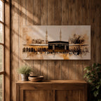 Panoramic painting of the Kaaba at Masjid al Haram in Mecca surrounded by mosque arches and tall minarets. The composition features the black cube structure at the center with pilgrims gathered in the courtyard, rendered in expressive brushstrokes with beige, brown, and gold tones.