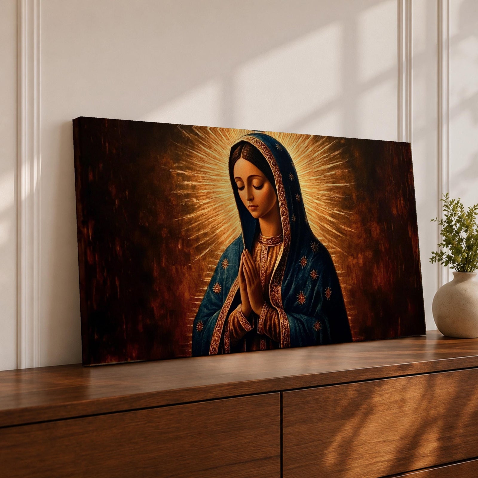 Panoramic religious painting of the Virgin Mary praying with hands together and head bowed, surrounded by a radiant golden halo against a warm dark background.