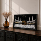 Panoramic artwork of the Kaaba at Masjid al-Haram in Mecca with black and gold accents surrounded by mosque arches and tall minarets against a dark night background.