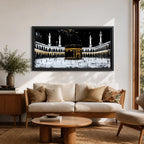 Panoramic artwork of the Kaaba at Masjid al-Haram in Mecca with black and gold accents surrounded by mosque arches and tall minarets against a dark night background.