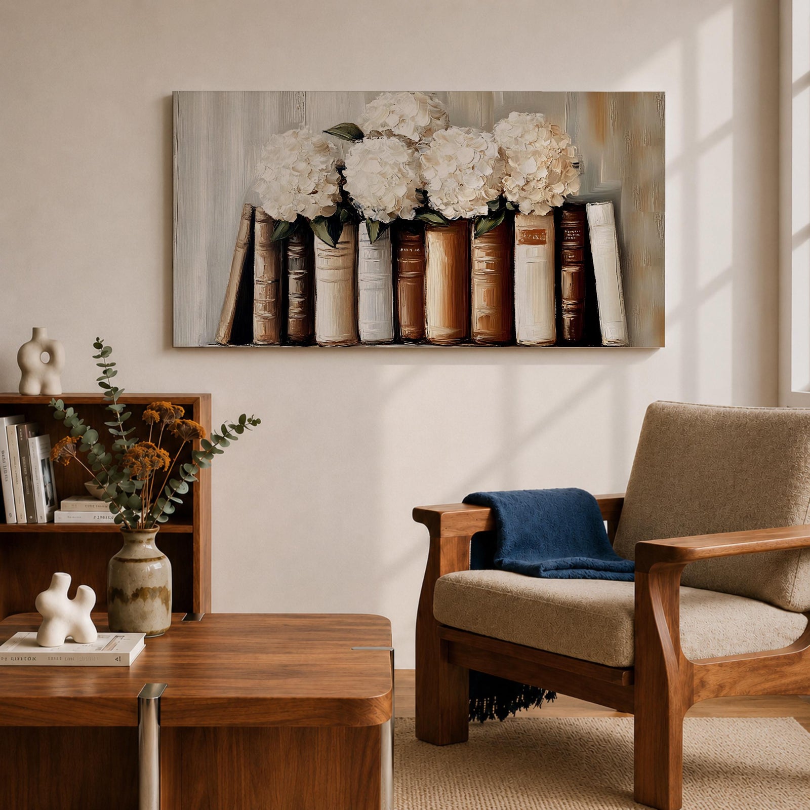 Panoramic still life painting of white hydrangea flowers arranged inside stacked vintage books with neutral beige and cream tones in a soft textured background.