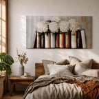 Panoramic still life painting of white hydrangea flowers arranged inside stacked vintage books with neutral beige and cream tones in a soft textured background.