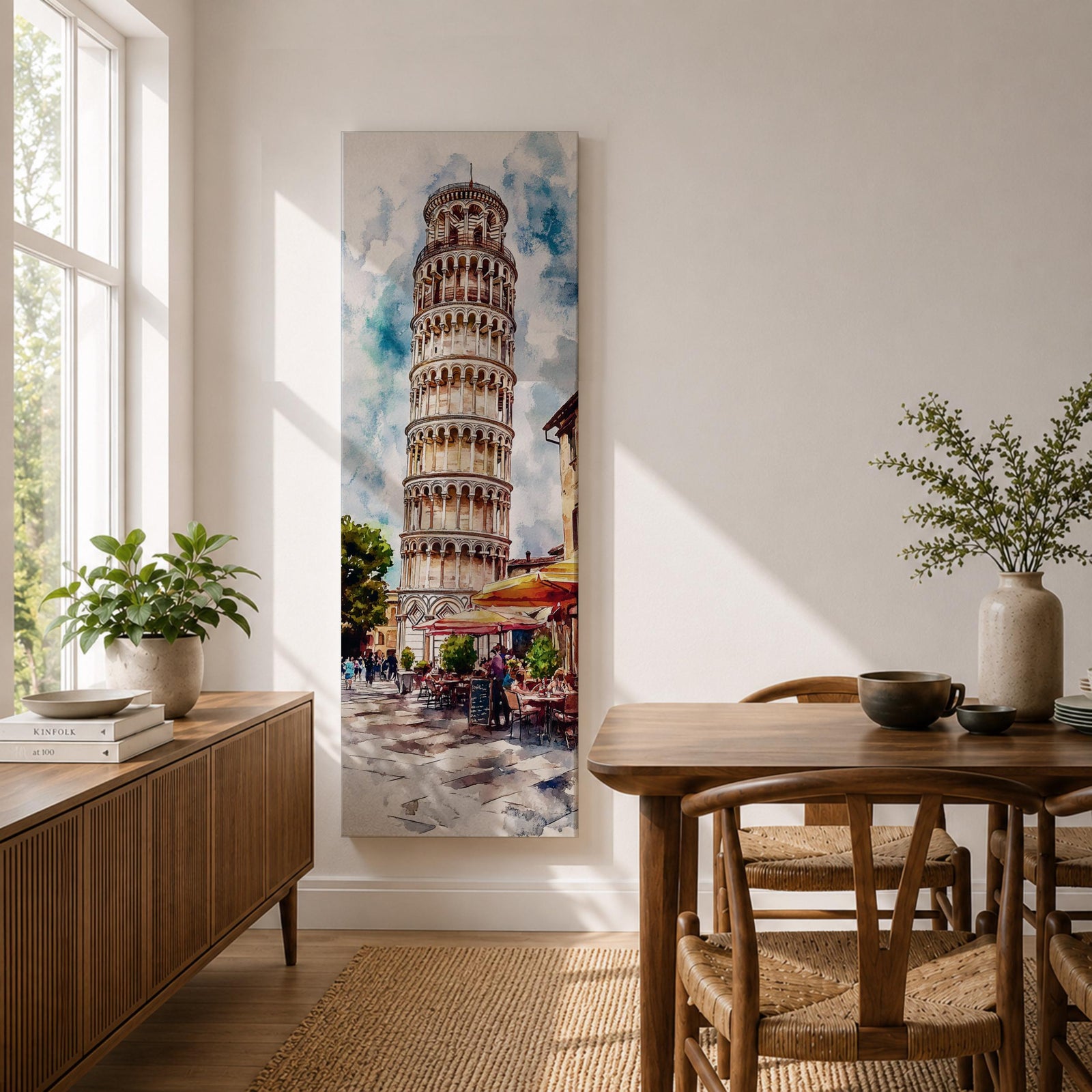 Long vertical watercolor style painting of the Leaning Tower rising above a lively Italian piazza with outdoor café tables and people walking along a stone street. The famous marble tower tilts gently against a bright sky while expressive brushstrokes capture the atmosphere of a historic Italian landmark and travel scene.