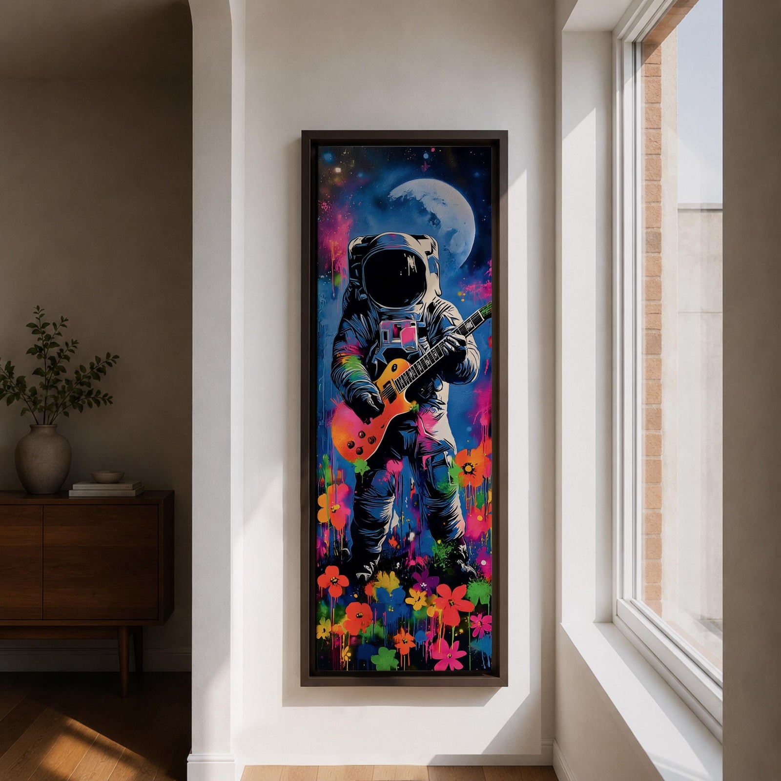 A tall vertical artwork shows an astronaut in a detailed space suit playing an electric guitar, set against a vivid cosmic backdrop with a glowing moon, deep blue sky, and splashes of neon pink, green, and orange paint, while bright flowers bloom at the base, blending surreal space imagery with street art style and bold expressive color.
