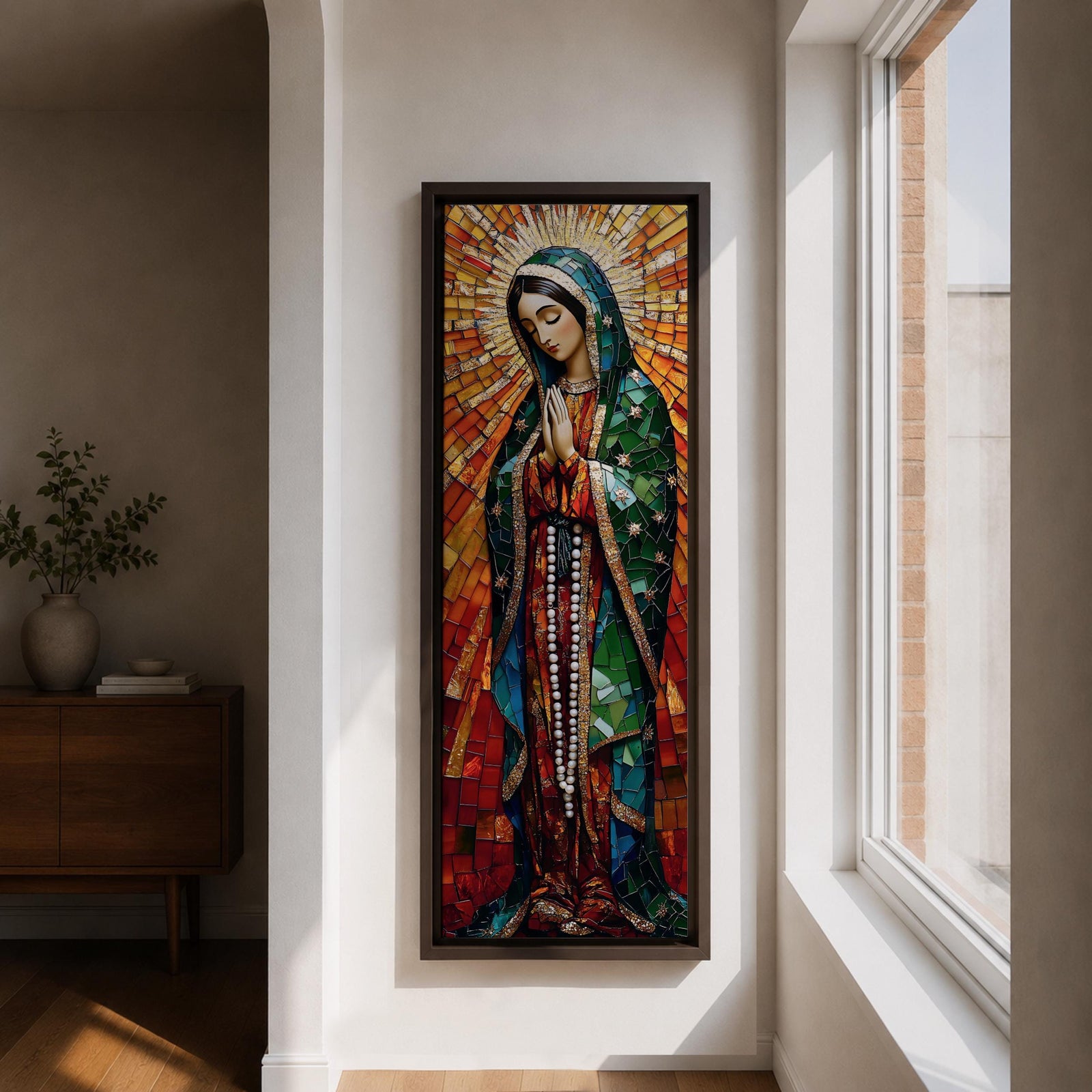 Long vertical stained glass style depiction of Our Lady of Guadalupe with hands clasped in prayer. She wears a green mantle decorated with stars and a red robe while radiant golden rays form a halo behind her, composed of colorful mosaic glass pieces forming a luminous devotional image.