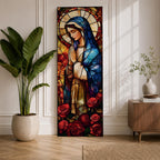 Long vertical stained glass style depiction of the Virgin Mary with hands clasped in prayer. She wears a blue mantle and cream robe while a circular halo glows behind her head and red roses bloom at her feet, all formed with colorful glass segments in a luminous devotional composition.