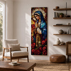 Long vertical stained glass style depiction of the Virgin Mary with hands clasped in prayer. She wears a blue mantle and cream robe while a circular halo glows behind her head and red roses bloom at her feet, all formed with colorful glass segments in a luminous devotional composition.
