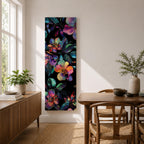 Tall vertical botanical artwork featuring glowing neon flowers in vibrant rainbow colors against a deep black background. Large luminous blossoms in pink, orange, purple, and blue are surrounded by detailed leaves, creating a modern floral composition with bold contrast and iridescent color transitions.